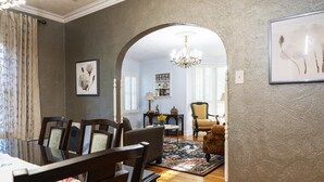 Uma área de refeições com uma mesa de vidro, cadeiras de madeira e um tapete estampado.