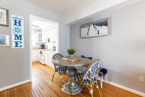 A dining area with a round table, chairs, and a view into the kitchen.