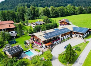 A residential area with multiple houses, a swimming pool, and solar panels on the roofs.