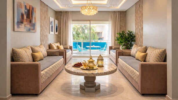 A modern living room with two sofas, a round coffee table, and a chandelier. - Luxurious Apartment in Sidi Bou Zid with Garden View (sidi bou zid)
