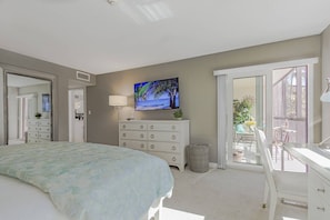 A bedroom with a bed, a dresser, a television, and a balcony with outdoor furniture. - Beachfront at Siesta Breaker | 2nd Fl | Gulf Views (Sarasota)