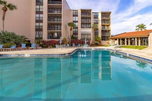A hotel pool area with a clear blue pool, lounge chairs, and a building with multiple balconies. - Beachfront at Siesta Breaker | 2nd Fl | Gulf Views (Sarasota)