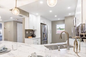 A modern kitchen with white cabinets, stainless steel appliances, and a marble countertop. - Beachfront at Siesta Breaker | 2nd Fl | Gulf Views (Sarasota)