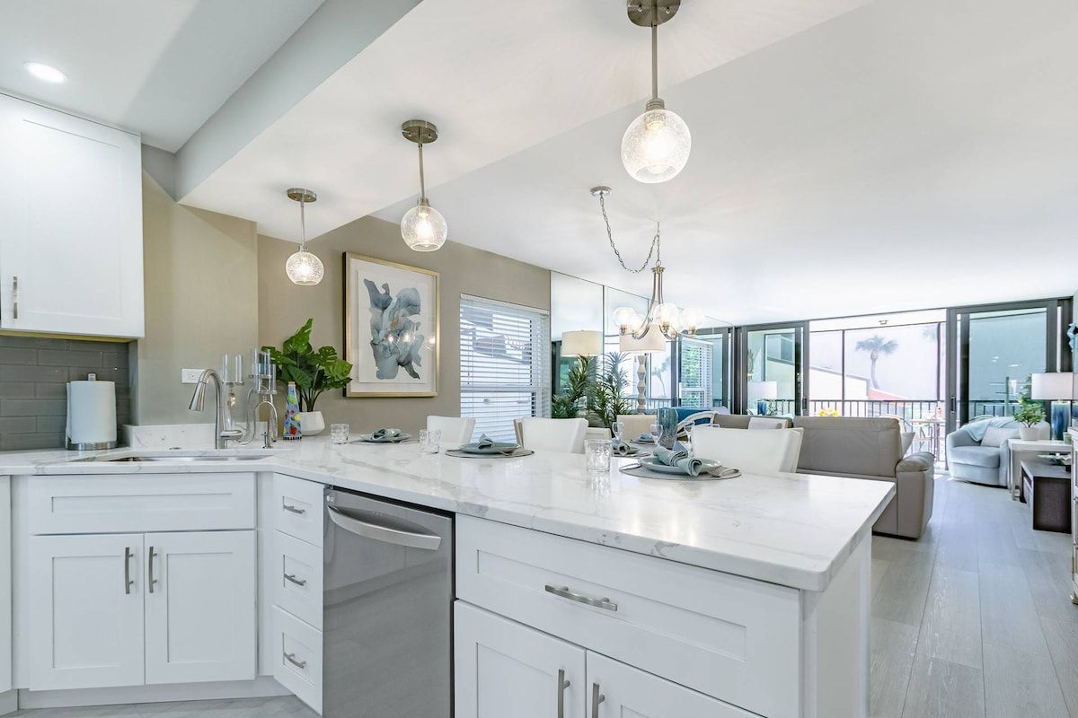 A modern kitchen with white cabinetry, a central island, and pendant lighting.