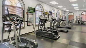Un gimnasio con cintas de correr, elípticas y máquinas de pesas.