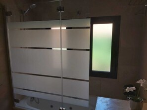 A bathroom with a glass partition, a small window, and a potted orchid. - Top Ferienwohnung mit Pool in Spanien, Andalusien an der Costa del Sol (San Luis de Sabinillas)