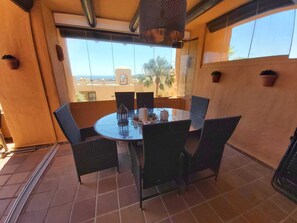 A round table with chairs on a balcony with a view of buildings and palm trees. - Top Ferienwohnung mit Pool in Spanien, Andalusien an der Costa del Sol (San Luis de Sabinillas)