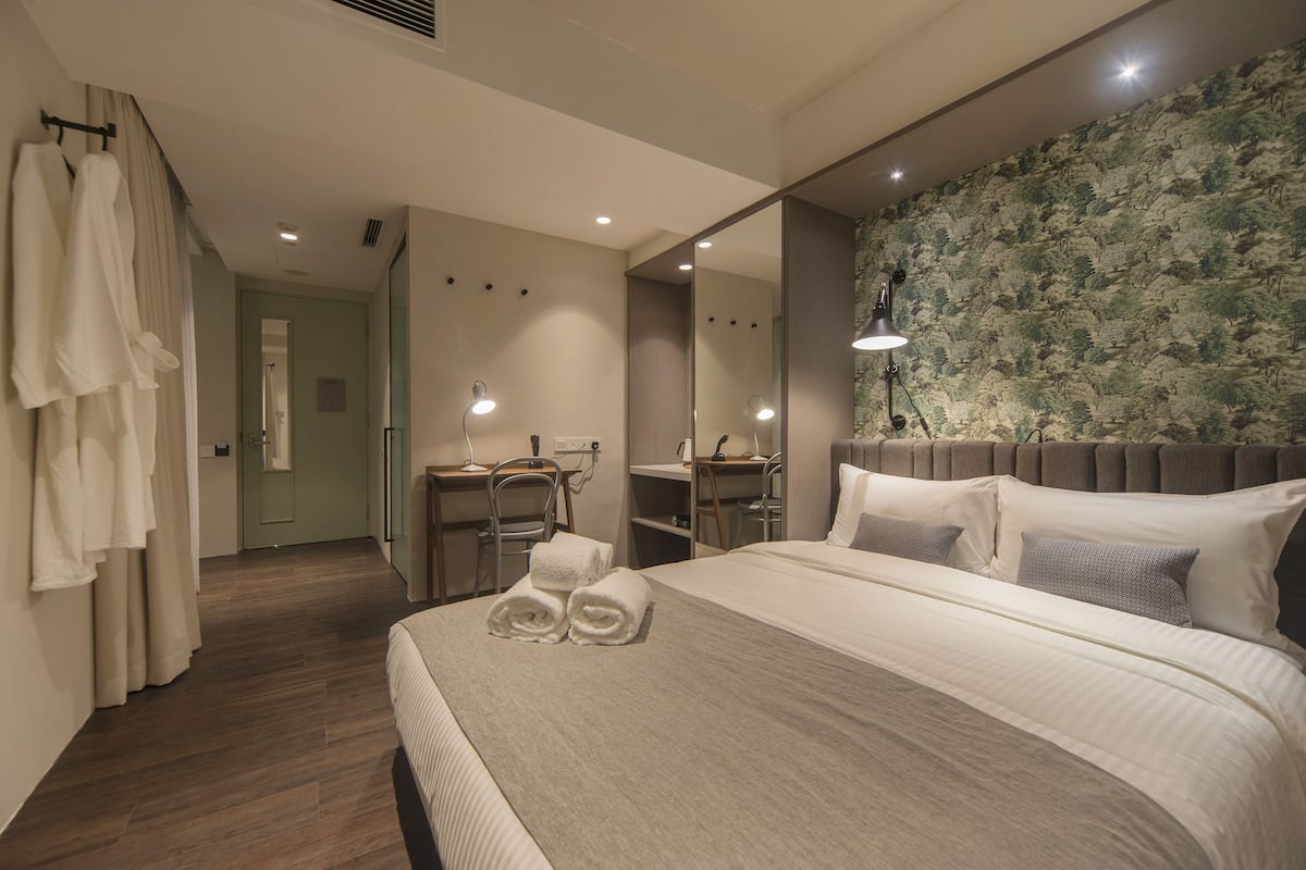 Une chambre d’hôtel avec un grand lit, un bureau, une chaise, un miroir et un espace douche.