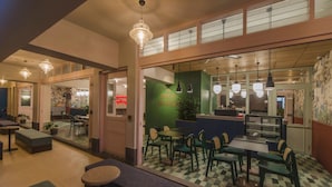 Un restaurante con piso a cuadros, sillas verde y negro, y una barra con fondo verde.