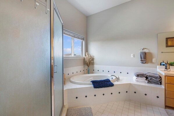 Un baño con bañera, una ventana, un perchero para toallas y un lavamanos.