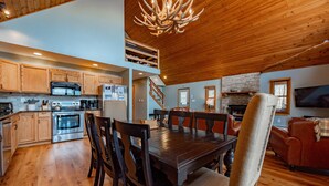 A spacious living area with a wooden dining table, chairs, and a fireplace. - Rustic Woodsy Getaway w/Hot Tub & Fireplace (Oakland)