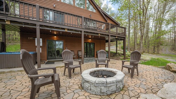 A cabin with a stone patio, outdoor seating, and a fire pit. - Rustic Woodsy Getaway w/Hot Tub & Fireplace (Oakland)