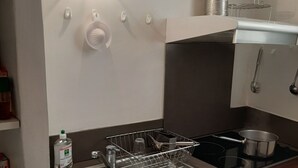 Una cocina compacta con un lavamanos de acero inoxidable, un escurreplatos, una estufa y un microondas.