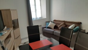 Una sala de estar con un sofá, dos sillones, una mesa de centro y un televisor sobre un mueble de madera.