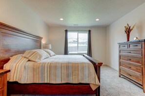 A bedroom with a wooden bed, a dresser, and a window with curtains.