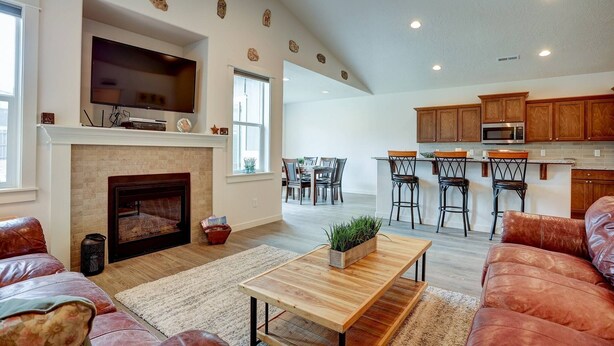 A spacious living room with a fireplace, a TV mounted above it, and a dining area with a kitchen in the background. - Fantastic Family Friendly Home w/ Moutain View, Huge Fenced yard, Private Backyard and Patio, A/ (Redmond)