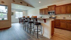 A kitchen with wooden cabinets, a microwave, and a bar area with stools. - Fantastic Family Friendly Home w/ Moutain View, Huge Fenced yard, Private Backyard and Patio, A/ (Redmond)