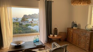 Una sala de estar acogedora con vista al mar, un mueble de madera y una mesa redonda con adornos.