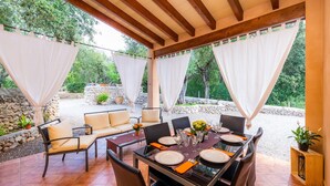 Un patio al aire libre con una mesa lista para comer, rodeado de sillas y un sofá.