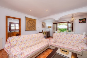 A living room with two sofas, a coffee table, a lamp, a painting, and a view of the outside.