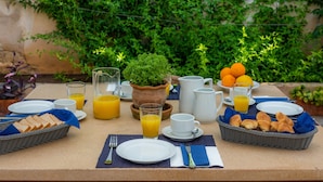 Ein Frühstückstisch mit Tellern, Gläsern und einem Korb mit Brot und Croissants.