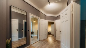 A hallway with wooden flooring, white doors, and a large mirror on the left. - *Grand Botanical* 4-room apartment with kitchen - Luga Homes - Townhouse (Leipzig)