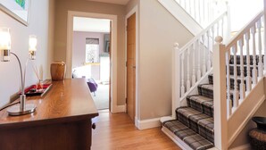 A hallway with a wooden desk, a staircase with patterned carpet, and a door leading to another room. - 3 Croftside (Aviemore)