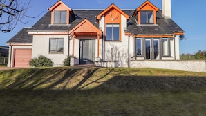 A modern two-story house with a sloped roof, large windows, and a chimney. - 3 Croftside (Aviemore)