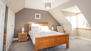 A bedroom with a wooden bed, bedside tables, a ceiling light, a window, and a door. - 3 Croftside (Aviemore)