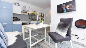 Una cucina moderna con mobili bianchi, un tavolo da pranzo e un televisore montato a parete.