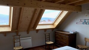 A room with a sloped ceiling, wooden beams, a bed, a dresser, two chairs, and a radiator. - Maison de Style Savoyard (Menthon-Saint-Bernard)