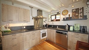 A modern kitchen with wooden cabinets, stainless steel appliances, and a wooden floor. - Maison de Style Savoyard (Menthon-Saint-Bernard)