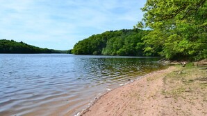A riverbank with a sandy shore and dense green trees in the background. - Large house in the Morvan (Lormes)