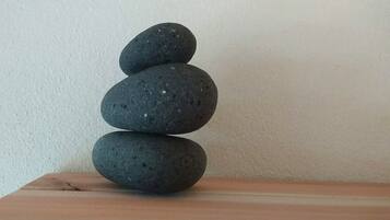 Trois pierres empilées sur une surface en bois, adossées à un mur uni.