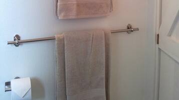 A bathroom with a towel rack holding two towels and a toilet paper holder.