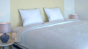 A neatly made bed with white bedding and a plain headboard, accompanied by two bedside lamps on either side.
