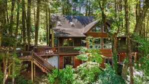 A two-story log cabin with a balcony and deck, surrounded by a forest. - Hazy Hideaway - Cherry Log, GA (Cherry Log)