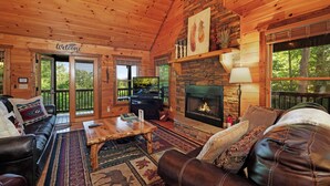 L’intérieur chaleureux d’un chalet avec une cheminée, des meubles en cuir et une pancarte « Bienvenue ».