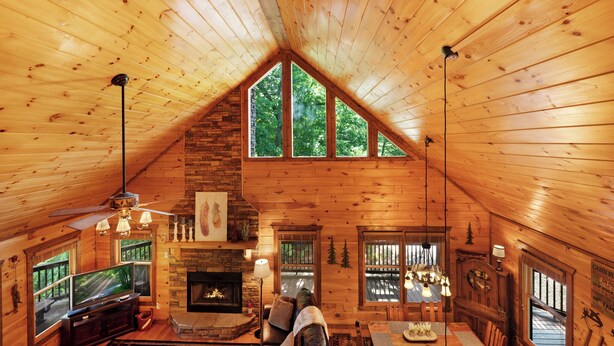 L’intérieur chaleureux d’un chalet avec une cheminée, des murs en bois et de grandes fenêtres donnant sur le paysage extérieur.