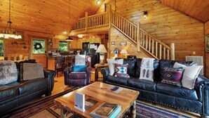 L’intérieur d’une cabane en rondins comprend un salon, un coin repas, une cuisine et un escalier menant à un étage supérieur.
