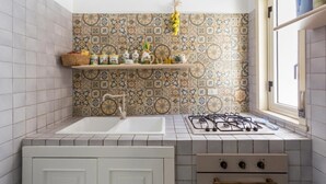 A kitchen with a tiled backsplash, a gas stove, a sink, and a window.