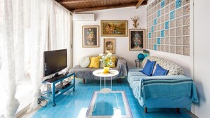 A living room with a TV, sofa, and artwork on the walls.