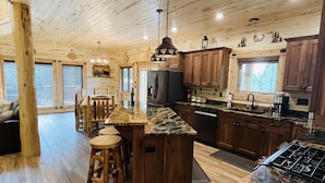 A spacious kitchen with wooden cabinetry, a central island, and a dining area with wooden stools.
