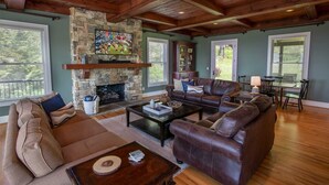 A spacious living room with a stone fireplace, leather sofas, and a dining area with a table and chairs. - Spectacular Estate with Breathtaking Views (Banner Elk)
