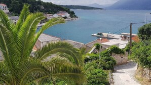 A coastal town with buildings along the waterfront, a clear view of the sea, and a mountainous backdrop. - Apartments Snjezana (Selca)
