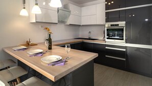 A modern kitchen with a central island, stainless steel appliances, and pendant lighting. - Apartments Snjezana (Selca)