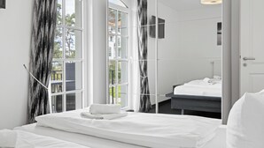 Habitación de hotel moderna con un amplio ventanal, cama con ropa blanca y vistas a la ciudad.