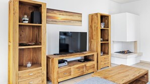 Una sala de estar moderna con una unidad de entretenimiento de madera, un televisor de pantalla plana y una chimenea.