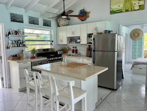 Una cocina moderna con armarios blancos, un refrigerador de acero inoxidable y una isla central con sillas.
