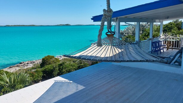 Eine Holzterrasse mit Blick auf türkisfarbenes Wasser und einen klaren Himmel.